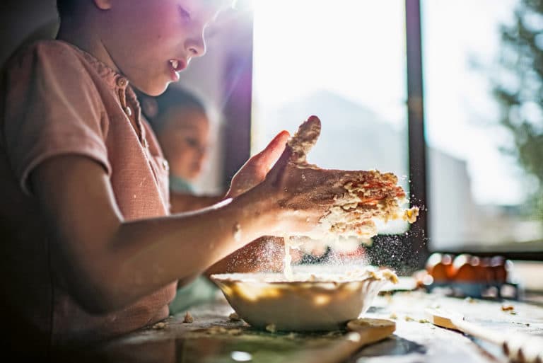 Kräuterbrot selber machen: Zwei Kinder kneten einen Teig in einer Schüssel