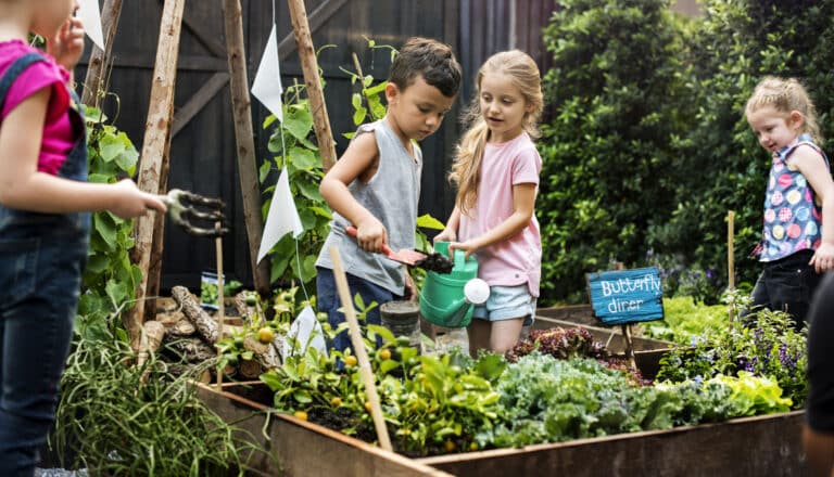Kinder fragen: 4 Kinder im Garten giessen ein Beet