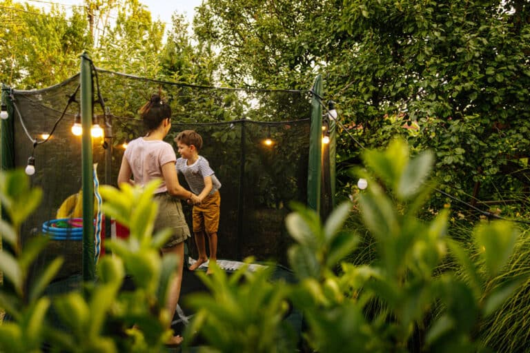 Kinderfreundlicher Garten: Kind hüpft mit Mutter auf einem Trampolin