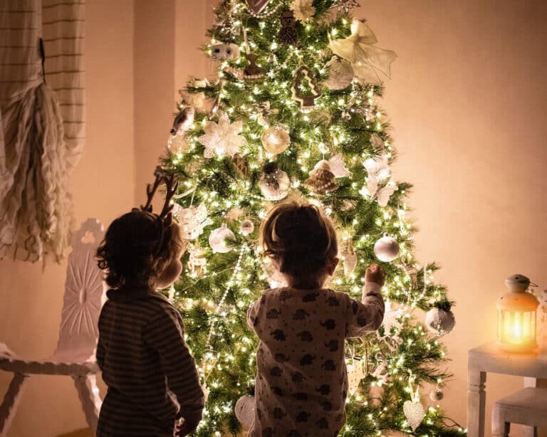Weihnachtszeit, Kinder vor einem geschmückten Weihnachtsbaum